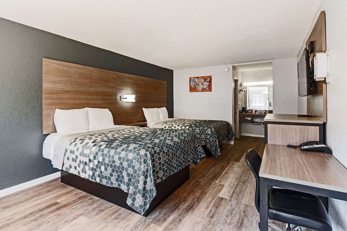 Habitación de hotel con cama, escritorio, silla y baño a la vista.