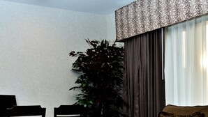 Ein Wohnzimmer mit einem dunkelbraunen Ledersofa, einem Holztisch und einem Essbereich mit Stühlen und einer Pflanze.
