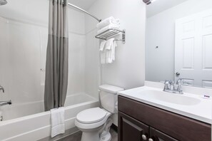 Een bad/douchecombinatie, handdoeken, zeep, toiletpapier