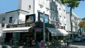 Un edificio blanco con un bar en la planta baja y un restaurante en el segundo piso.