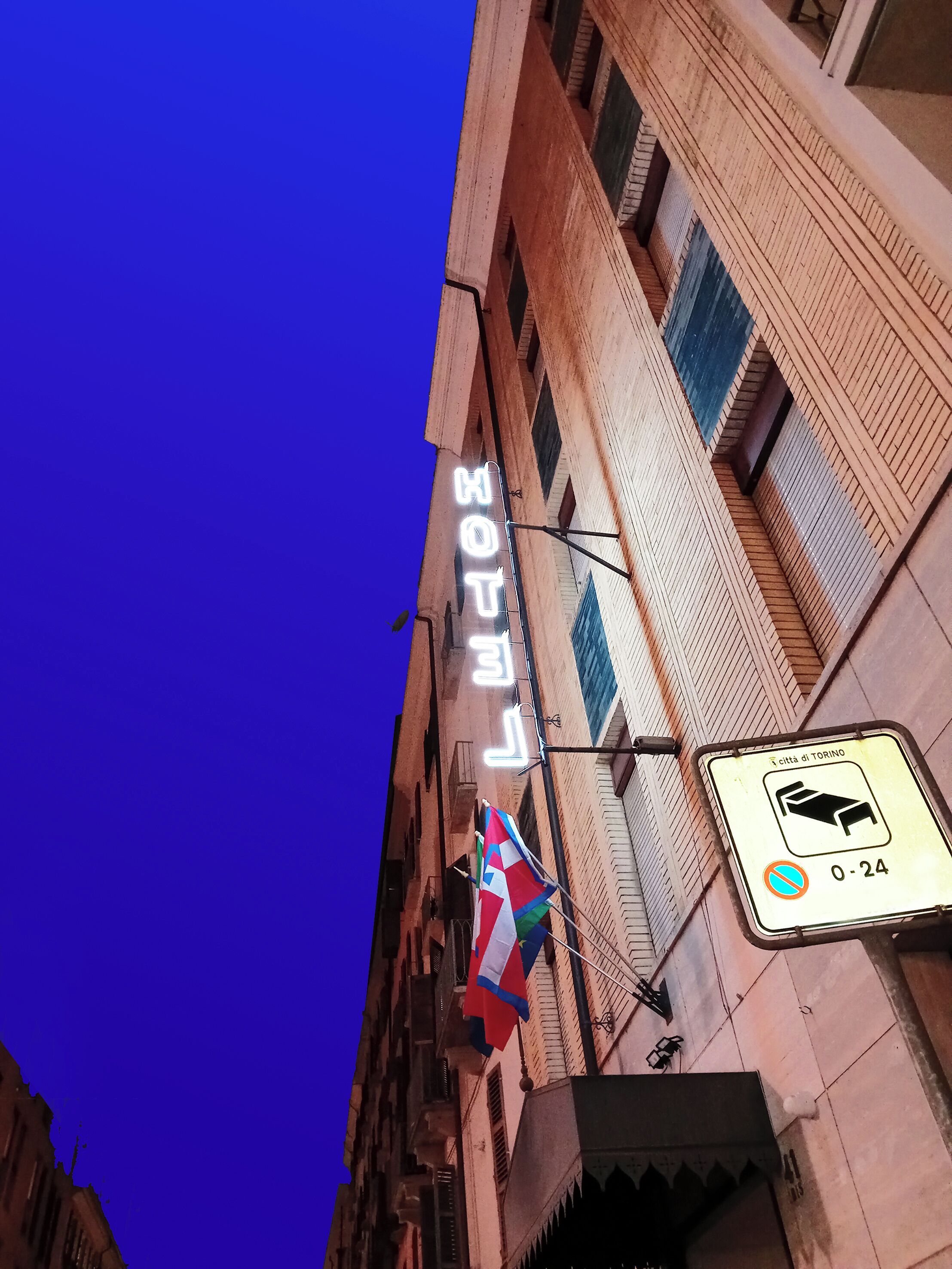 Ein Hotel-Schild mit einer Neonreklame für 'HOTEL' und einer Flagge.