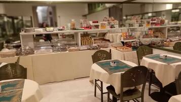 Ein Restaurant mit runden Tischen und Stühlen, einem Buffet mit Speisen und einer Theke mit verschiedenen Gerichten.
