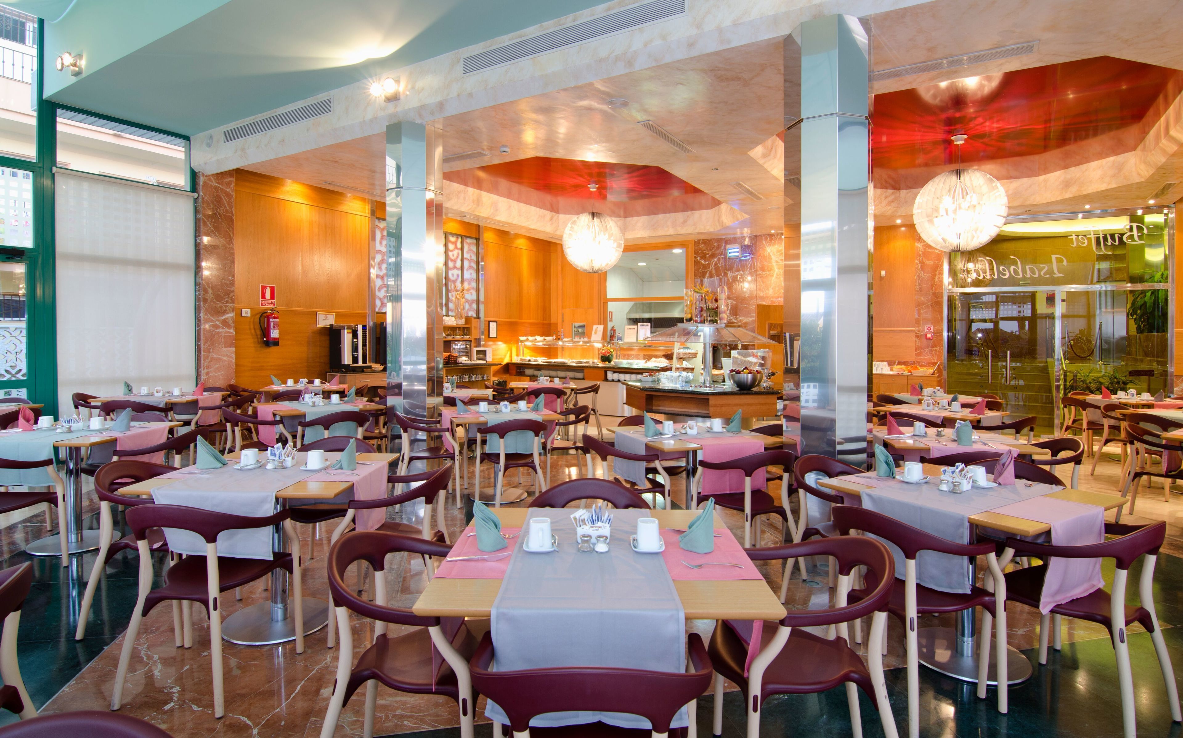 Un restaurant doté de plusieurs tables et chaises, d’un espace cuisine et d’un bar.