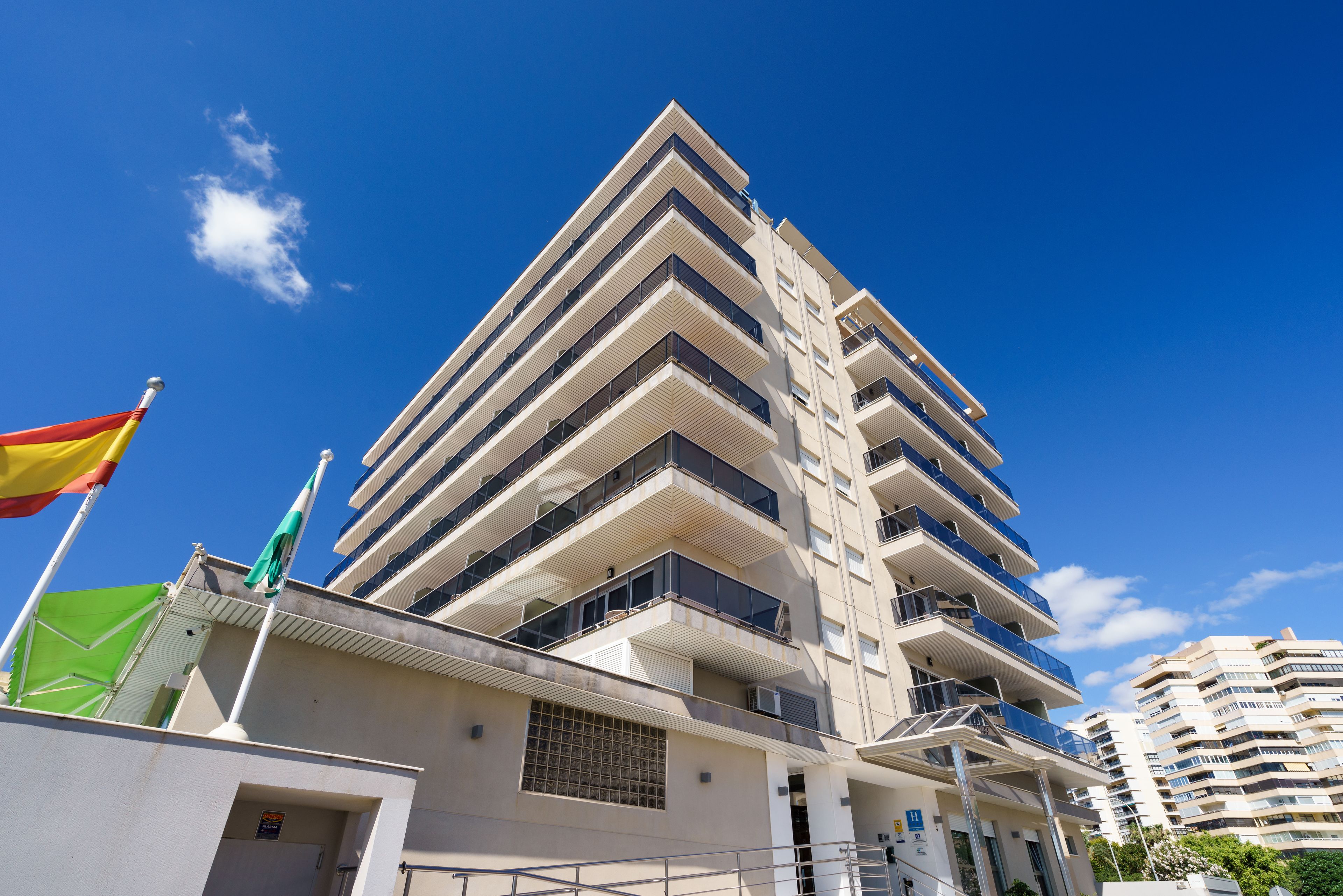 Un palazzo alto con numerosi balconi e un cielo azzurro intenso.