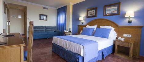 A hotel room with a large bed, a desk, and a chair. There are two bedside tables with lamps and a small table with a chair.