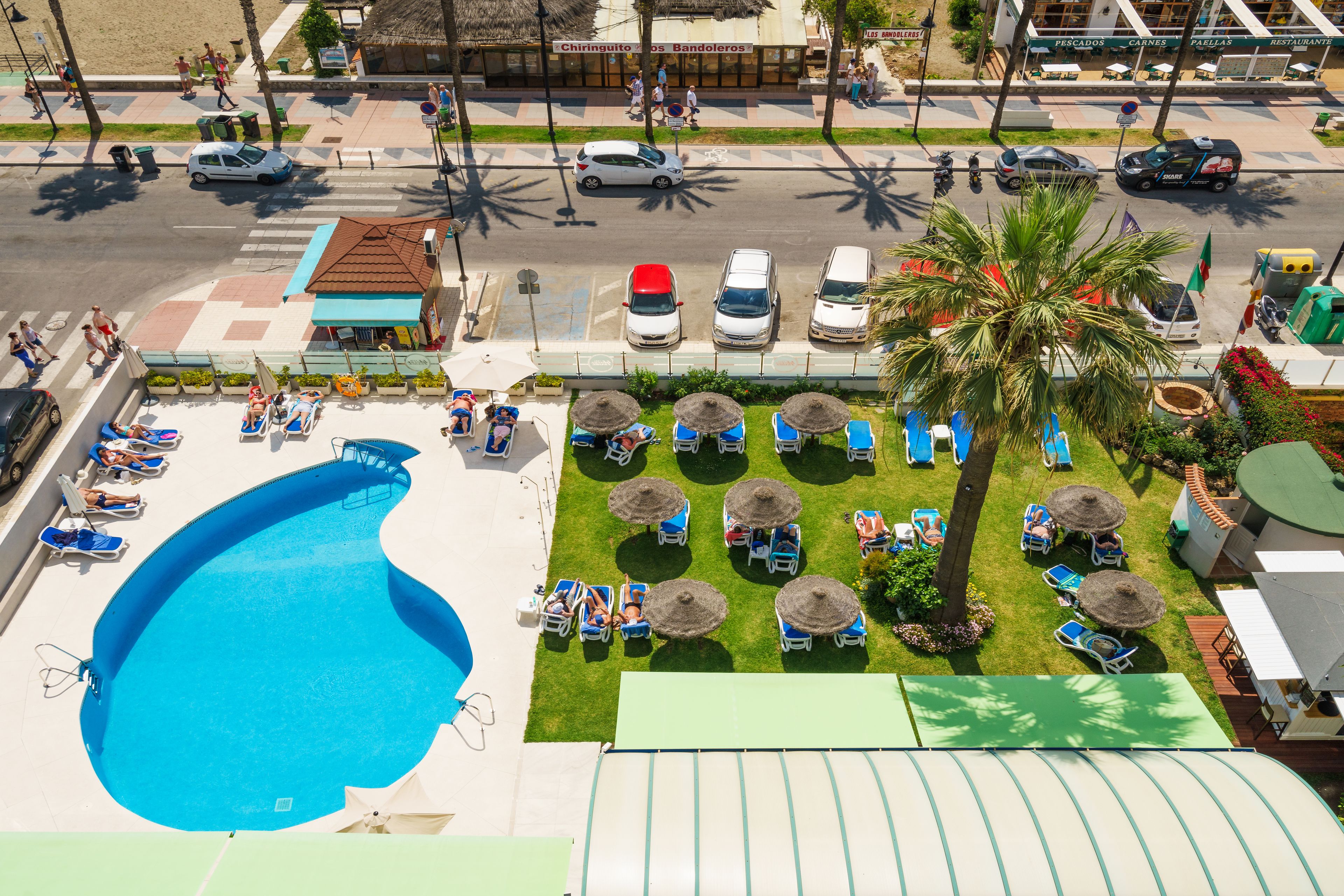 A pool area with lounge chairs, a swimming pool, and a small building.
