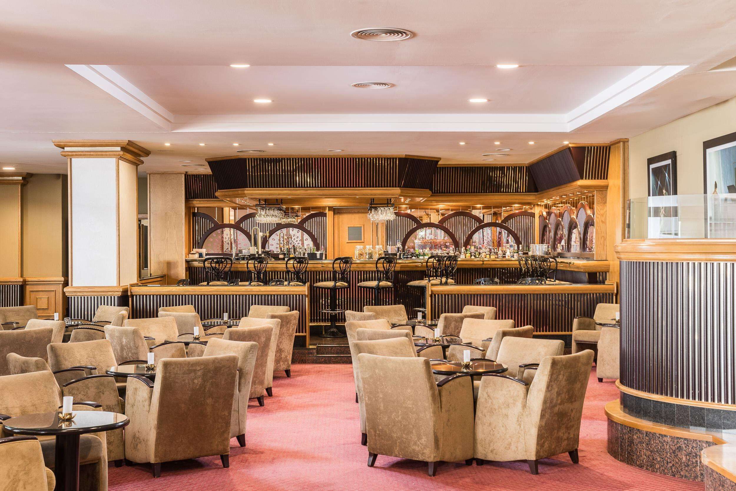 A hotel lobby with multiple seating areas, a bar, and a reception desk.