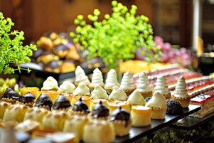 Et udvalg af desserter på et fad, herunder kager og småkager med forskellige toppings og pynt.