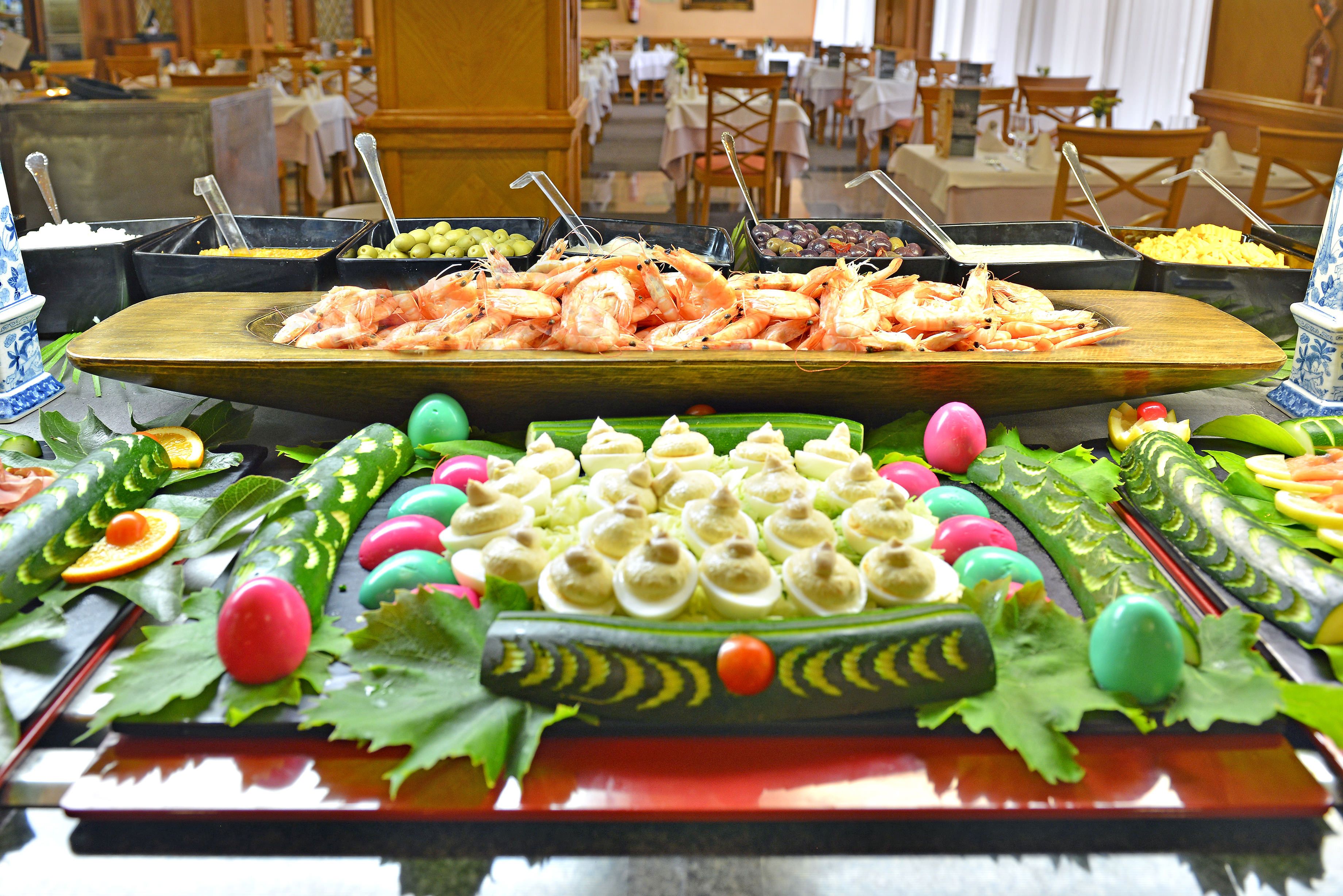 A buffet with various food items including shrimp, olives, and a variety of fruits and vegetables.