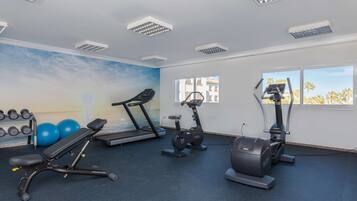 Une salle de sport équipée de tapis de course, d’un appareil elliptique et de poids libres.