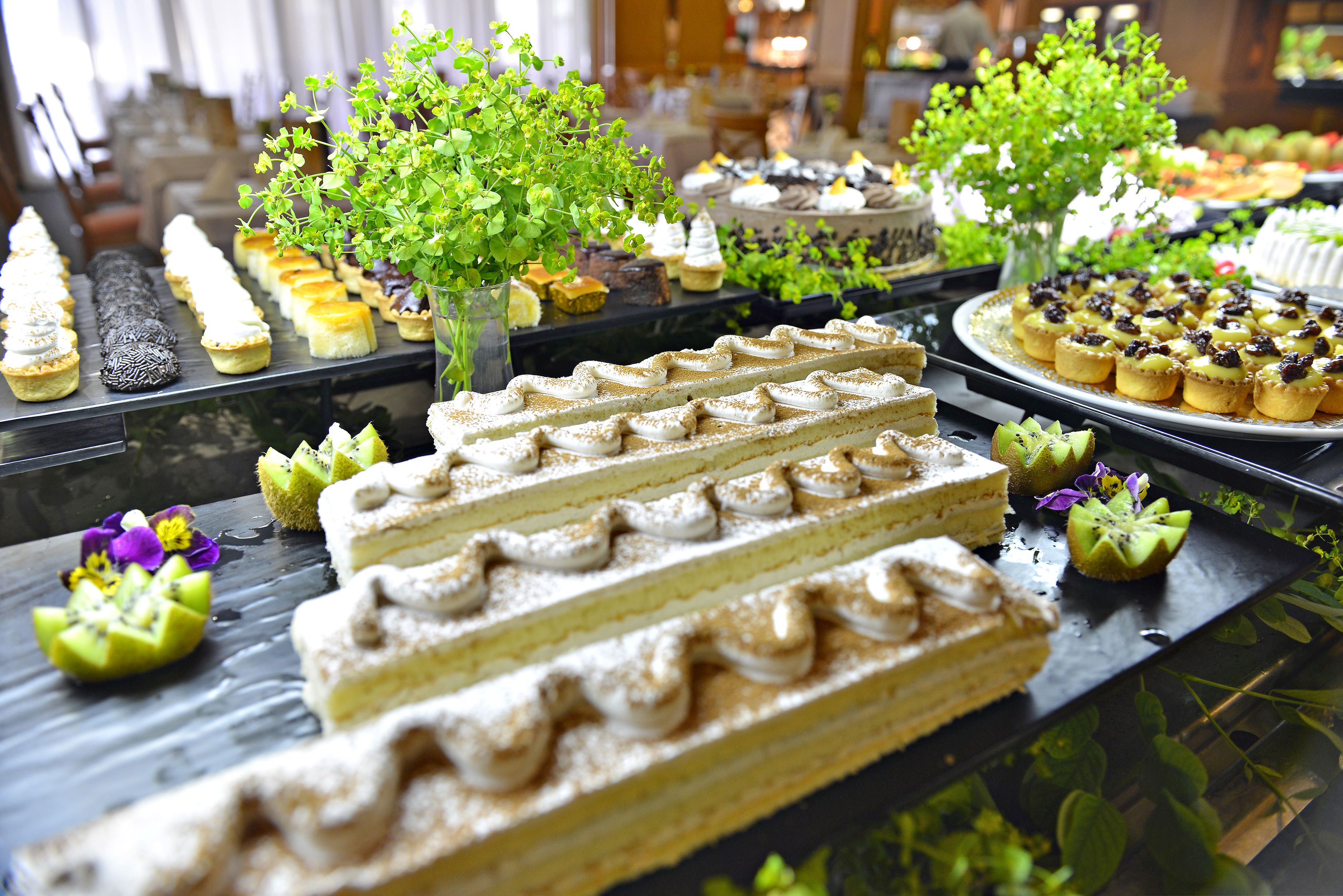 A buffet with various desserts and a decorative tree centerpiece.