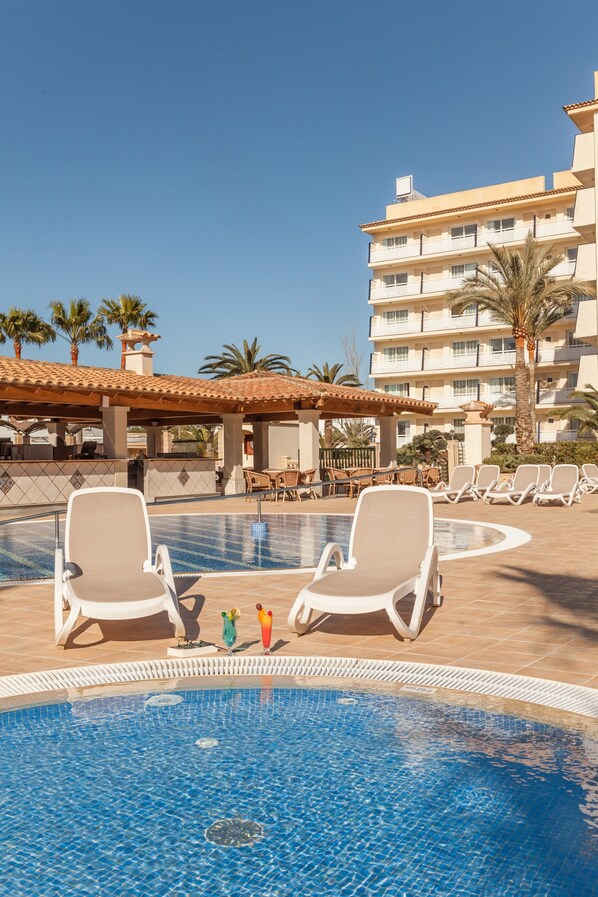 Una piscina al aire libre de temporada, sombrillas