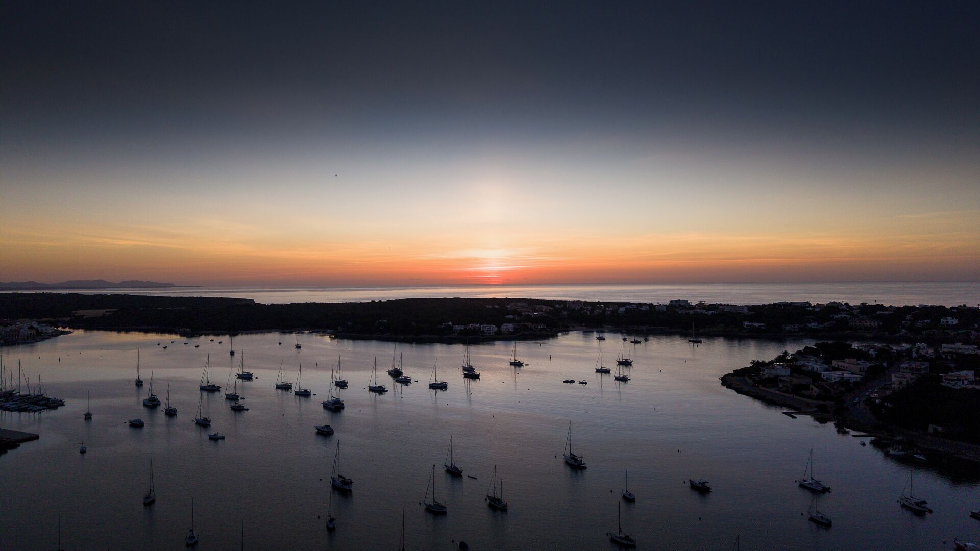 A coastal marina with multiple boats anchored in calm waters.
