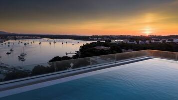 Una piscina en la azotea con vistas a un puerto deportivo al atardecer.
