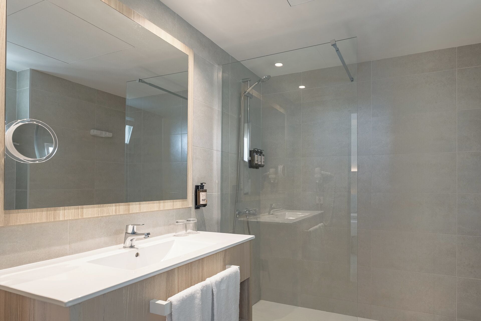 A modern bathroom with a large mirror, a sink, and a shower enclosure.
