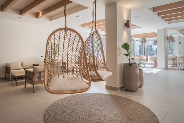 Interior moderno com uma cadeira suspensa, sofá e uma grande planta em vaso.