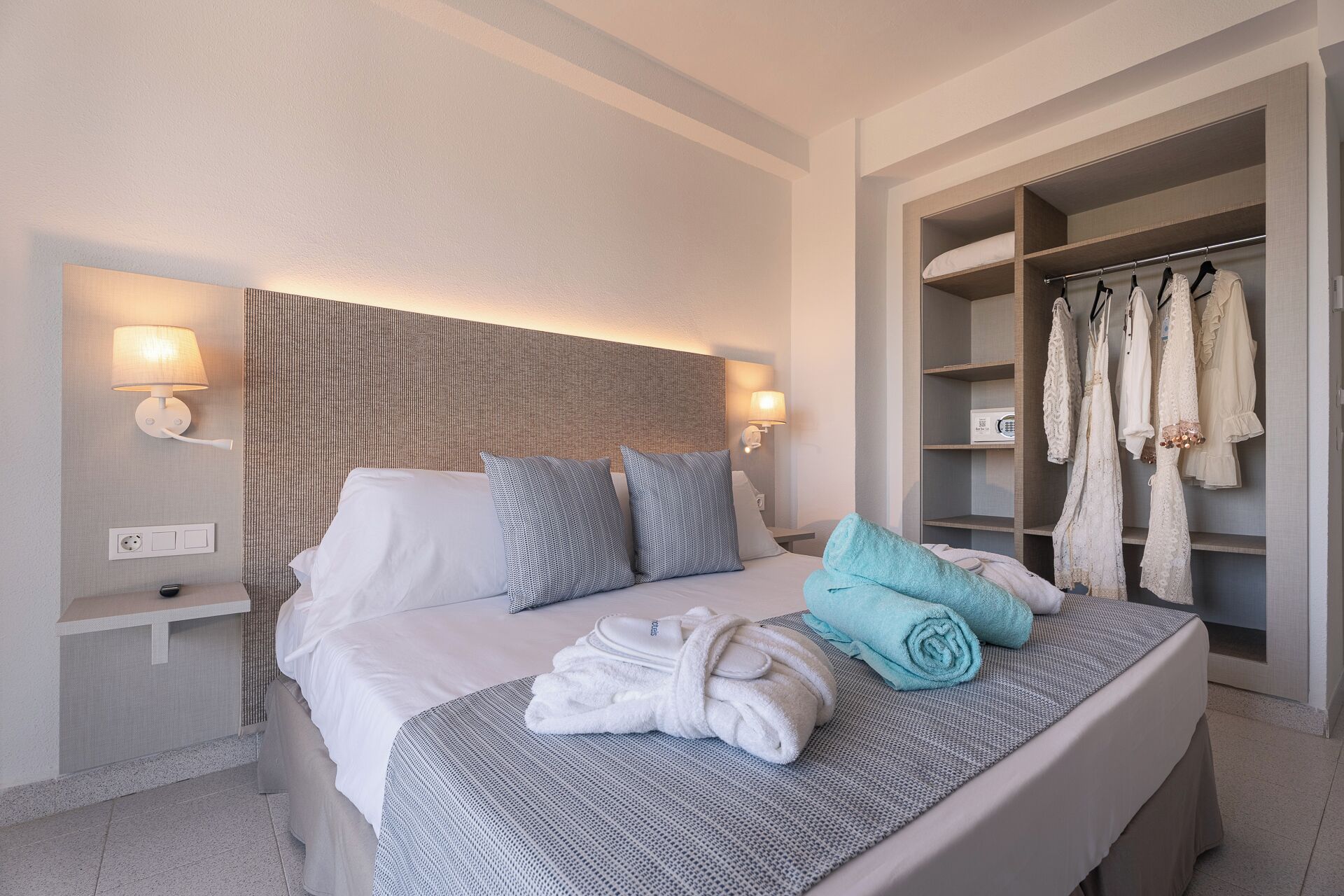 Ein Hotelzimmer mit Bett, Nachttischlampen, einem Kleiderschrank und einem Handtuchhalter.