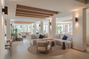 Un lobby espacioso con una zona de estar central, ventanas amplias y un diseño de techo moderno.