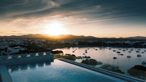 Une piscine donnant sur un port de plaisance, avec des bateaux et une vue sur la ville en arrière-plan.