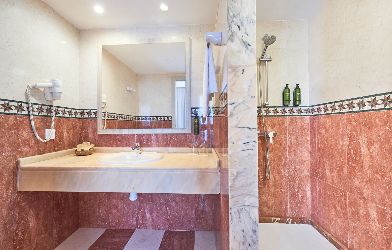 A bathroom with a marble sink, a mirror, a shower, and a bathtub.