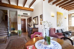 A spacious living room with a wooden dining table, comfortable seating, and a staircase leading to an upper level.