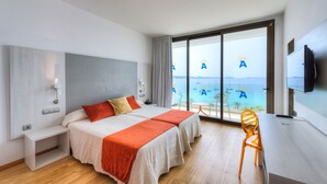 A hotel room with two beds, a desk, a chair, and a large window with a view of the sea. - Hotel Abrat (Sant Antoni de Portmany)