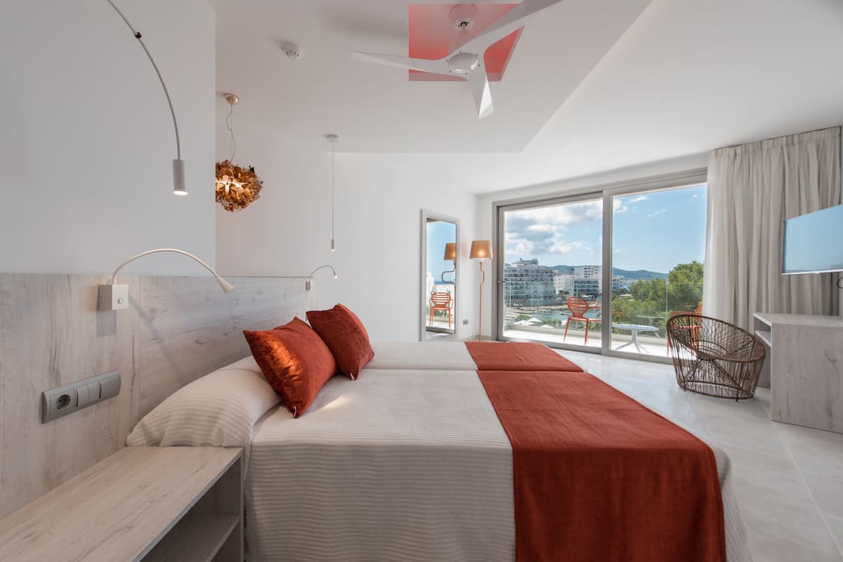 Moderni hotellihuone, jossa on suuri sänky, parveke, jolta on näkymä, ja televisio.