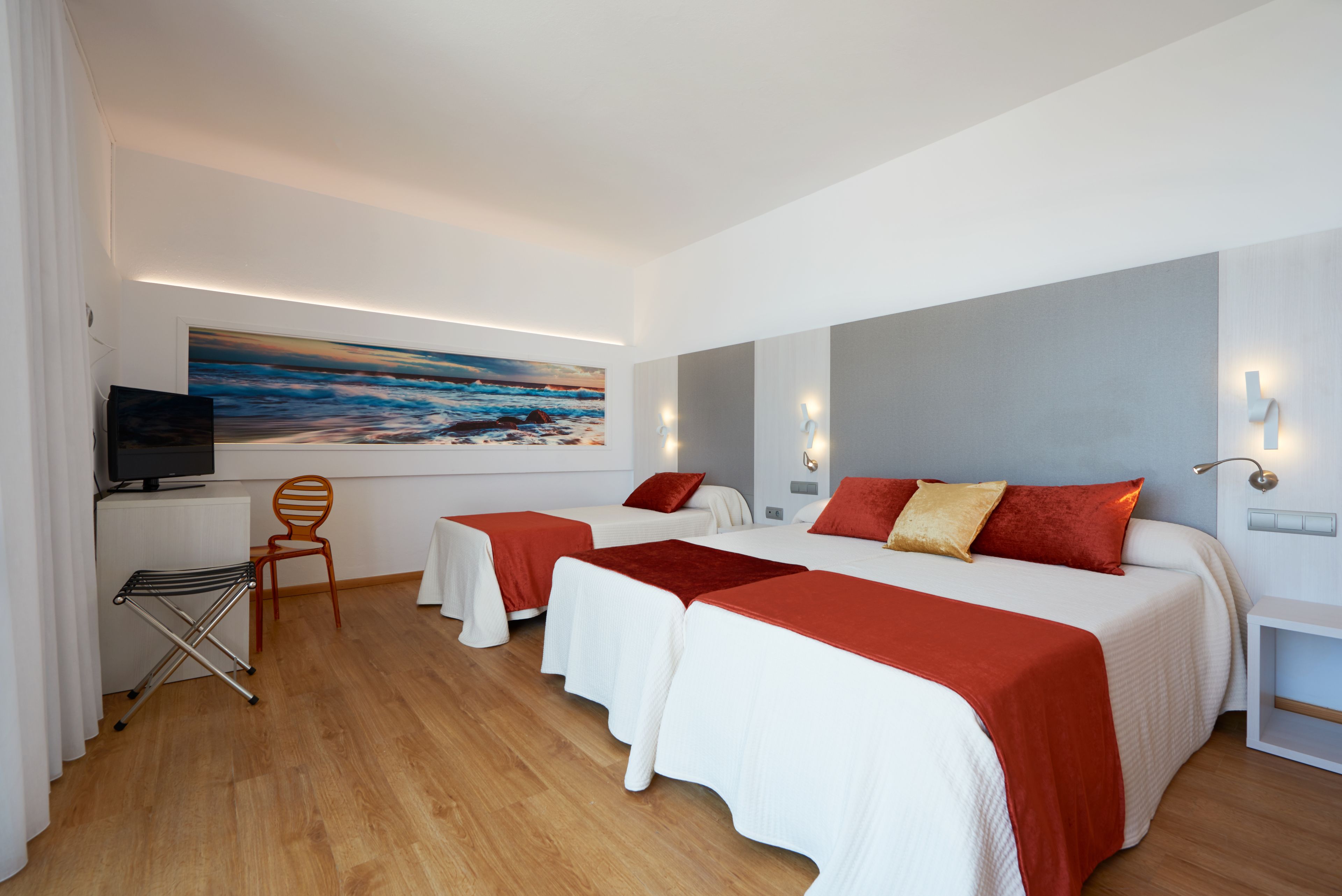 A hotel room with two beds, a TV, a painting, and a desk with a chair.