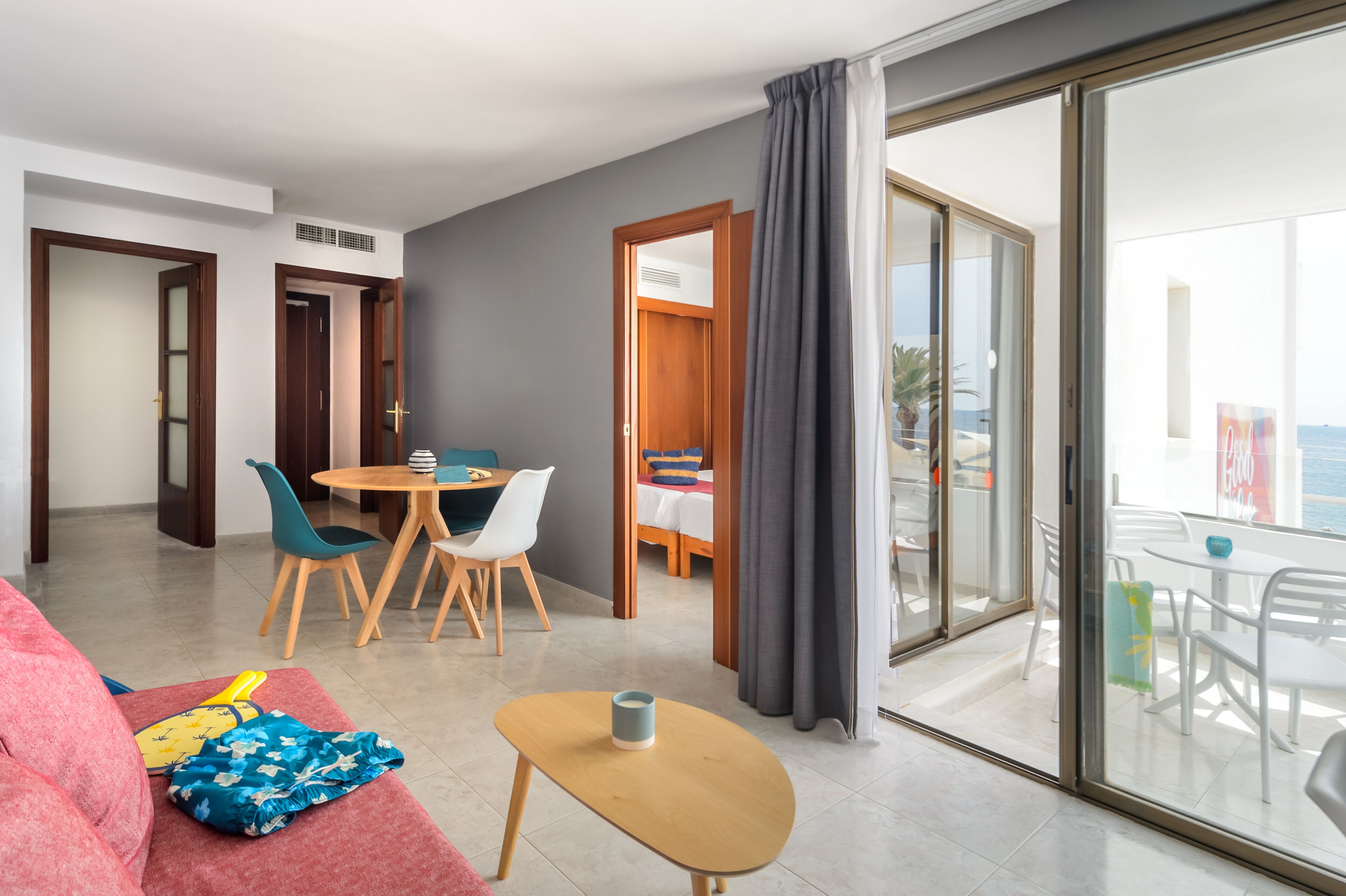 Una habitación de hotel moderna con balcón, zona de comedor y sala de estar.