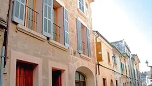 A narrow street with historic buildings, featuring arched doorways and traditional shutters. - L'Hostal hotel d'interior (Pollenca)
