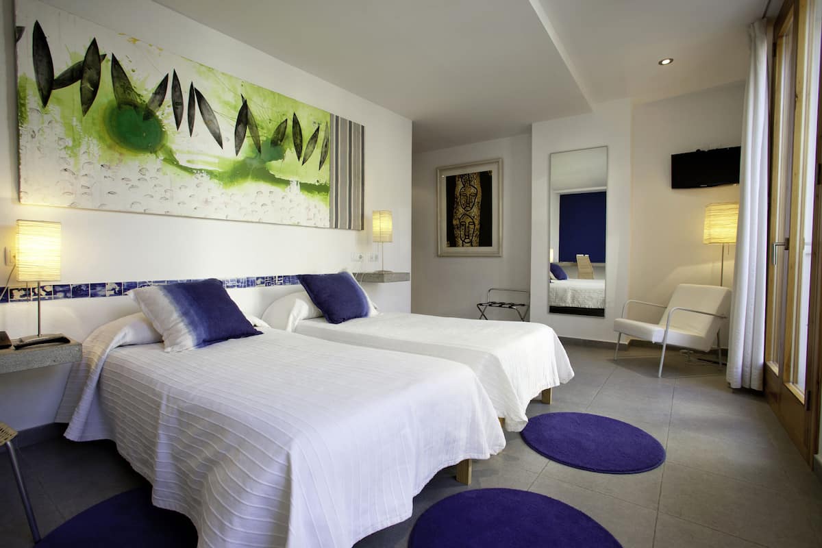 A hotel room with two beds, a large abstract painting, a television, and a chair.