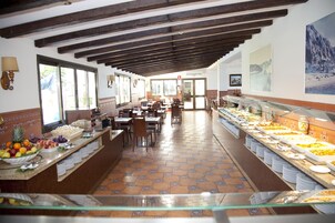 En buffet med et varieret udvalg af mad, et flisegulv og udsigt til spiseområdet gennem en glasvæg.