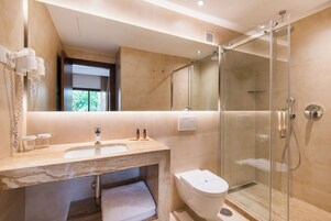 A modern bathroom with a glass-enclosed shower, a sink with a marble countertop, and a toilet.