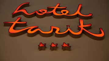 Een verlicht 3D-bord met de woorden 'hotel' en 'tarik' in een gestileerd lettertype, met daaronder drie rode sterren.