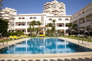 Una piscina al aire libre, sombrillas, sillones reclinables de piscina