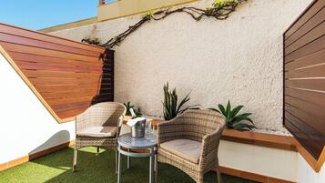 Un petit espace patio avec deux chaises en osier, une petite table ronde et une plante en pot.
