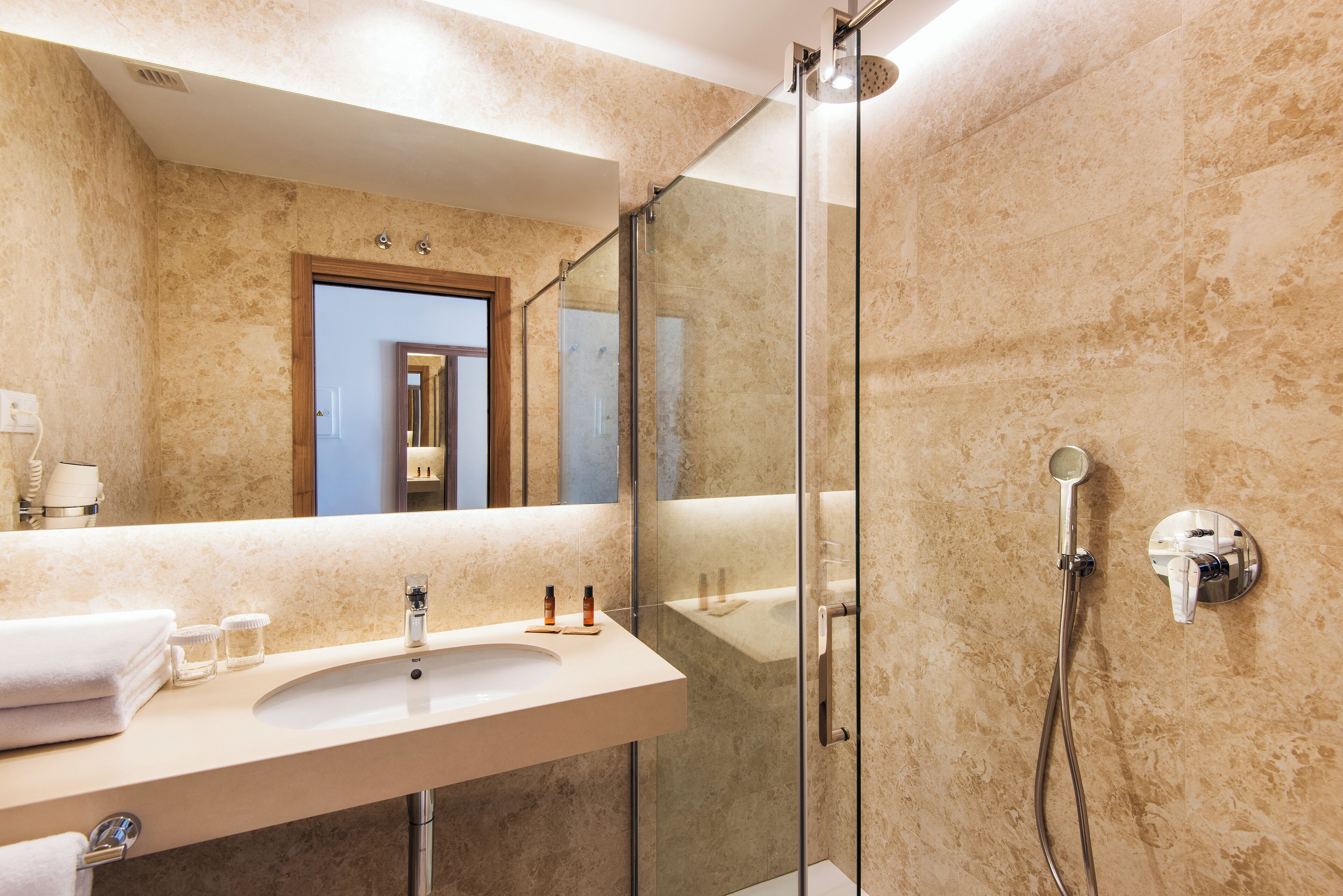 Un bagno moderno con doccia vetrata, uno specchio grande e un mobile lavabo con lavandino e portasciugamani.