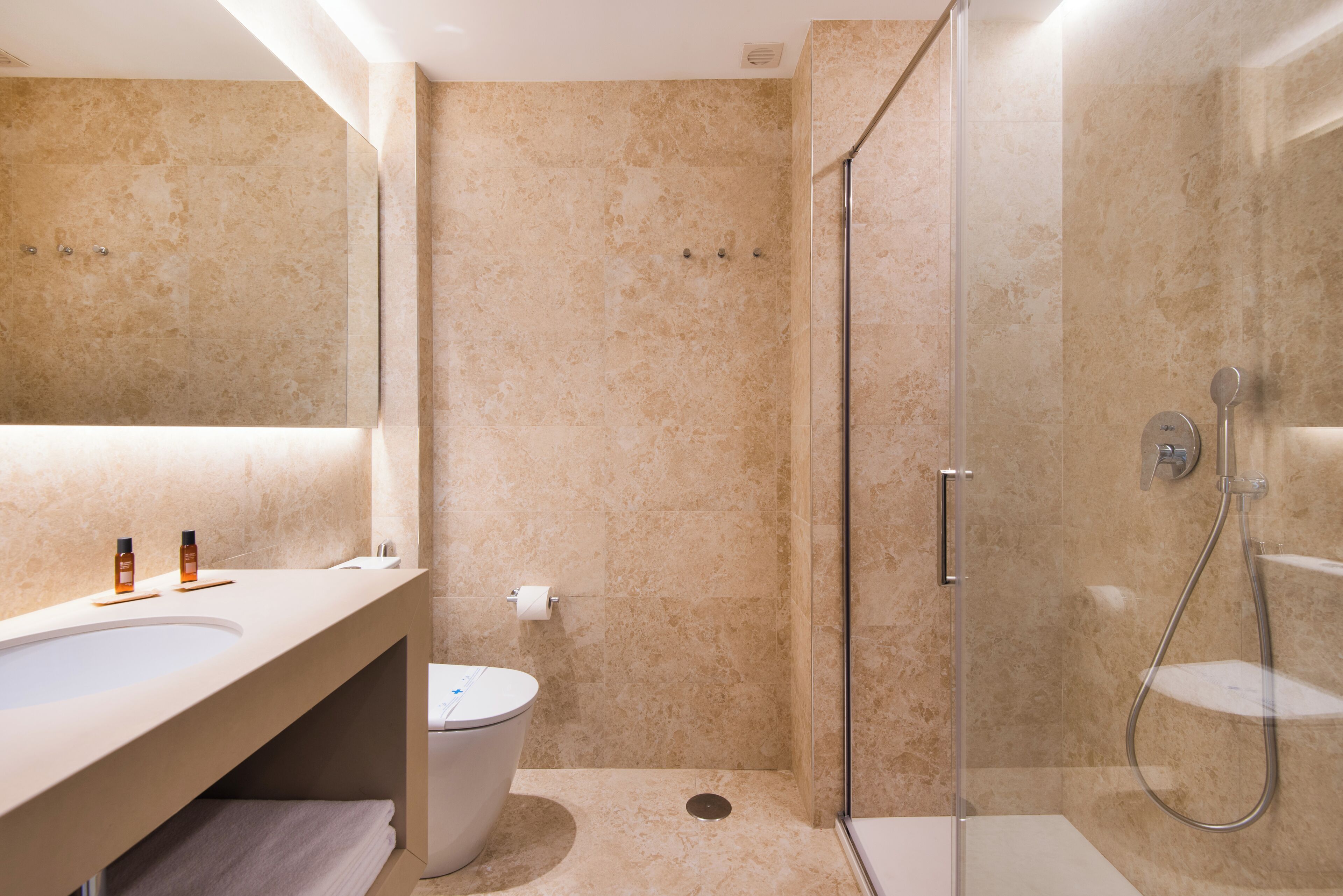 A modern bathroom with a large sink, a toilet, and a glass-enclosed shower area.