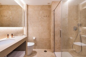A modern bathroom with a large sink, a toilet, and a glass-enclosed shower area.