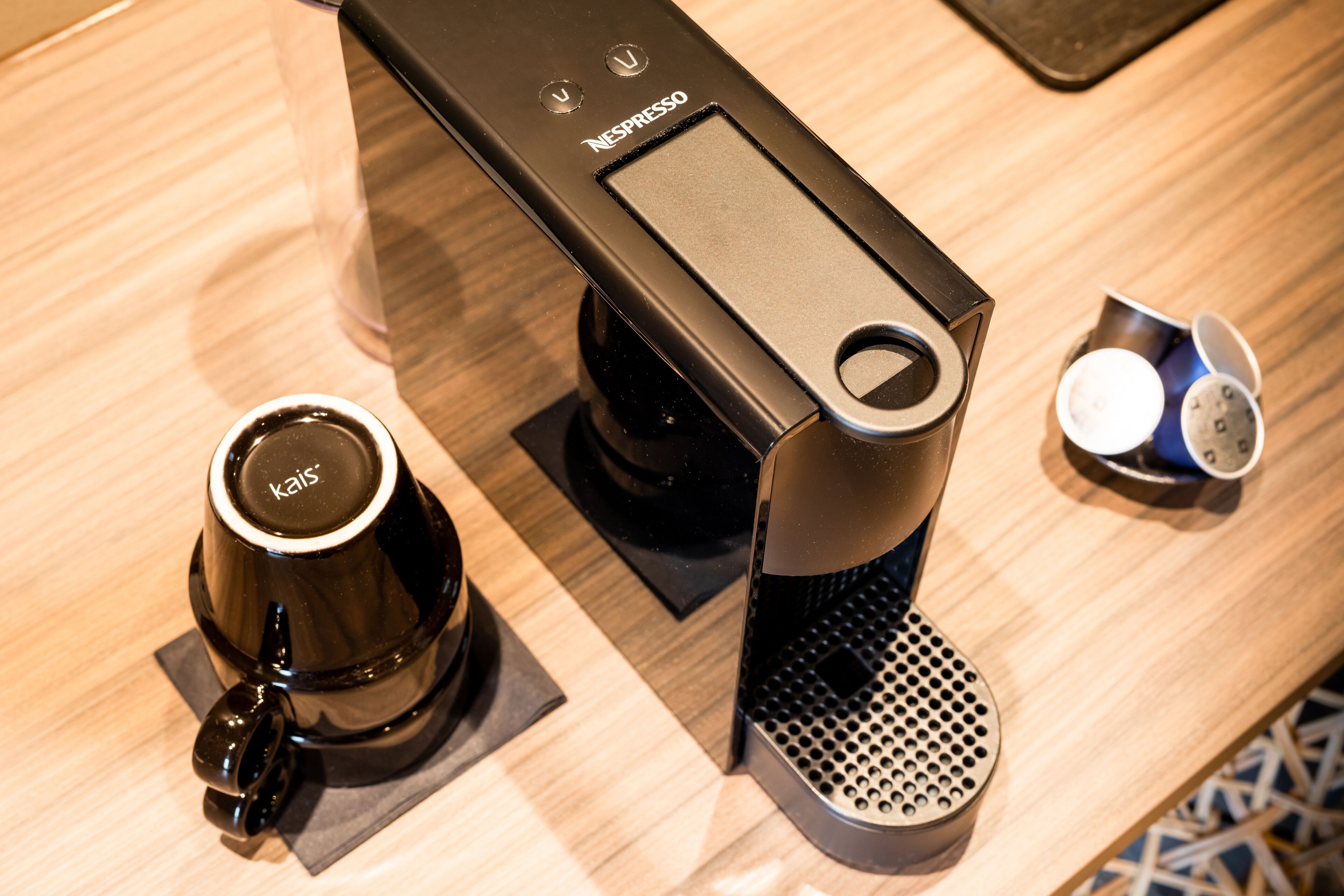 A Nespresso coffee machine with a single cup holder and a small cup of coffee on the counter.