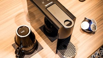 Una máquina de café Nespresso con un solo portavasos y una taza pequeña de café sobre la encimera.