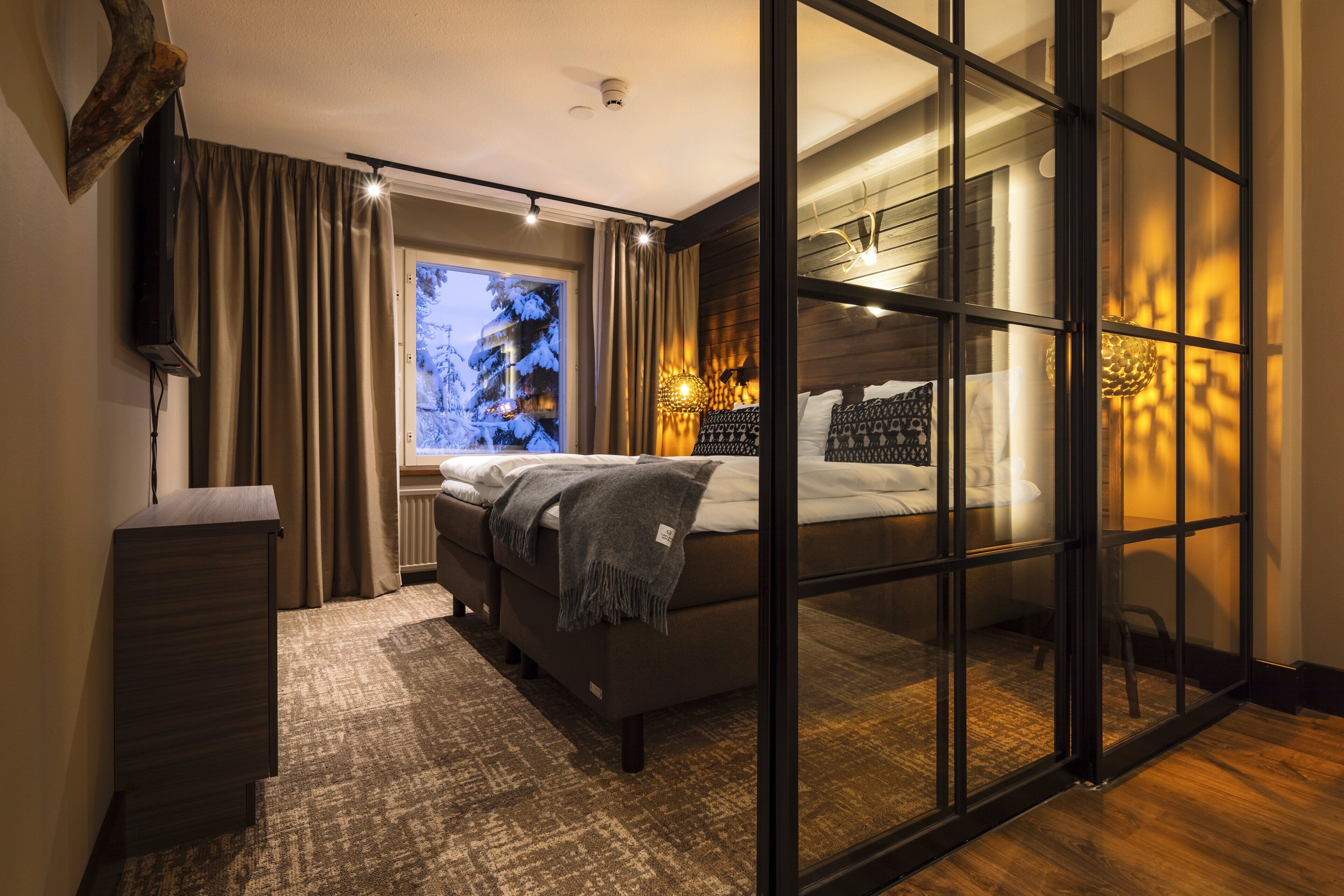 Ein modernes Schlafzimmer mit einem großen Bett, einem Schreibtisch und einer Glastür, die auf einen Balkon führt.