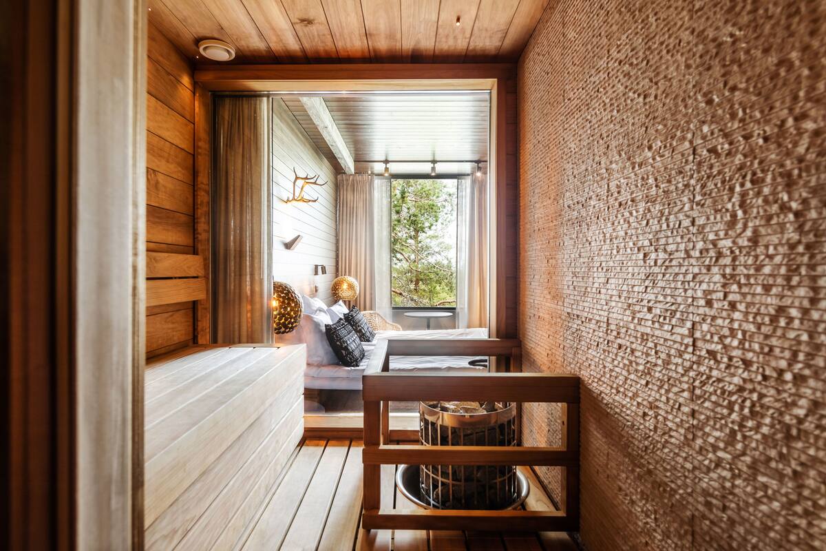 Un interior de madera acogedor con un banco, una chimenea y vistas al verde exterior.