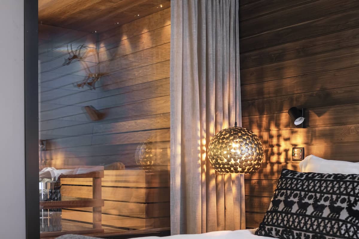 Un dormitorio moderno con una cama, una lámpara colgante y una pared de madera.
