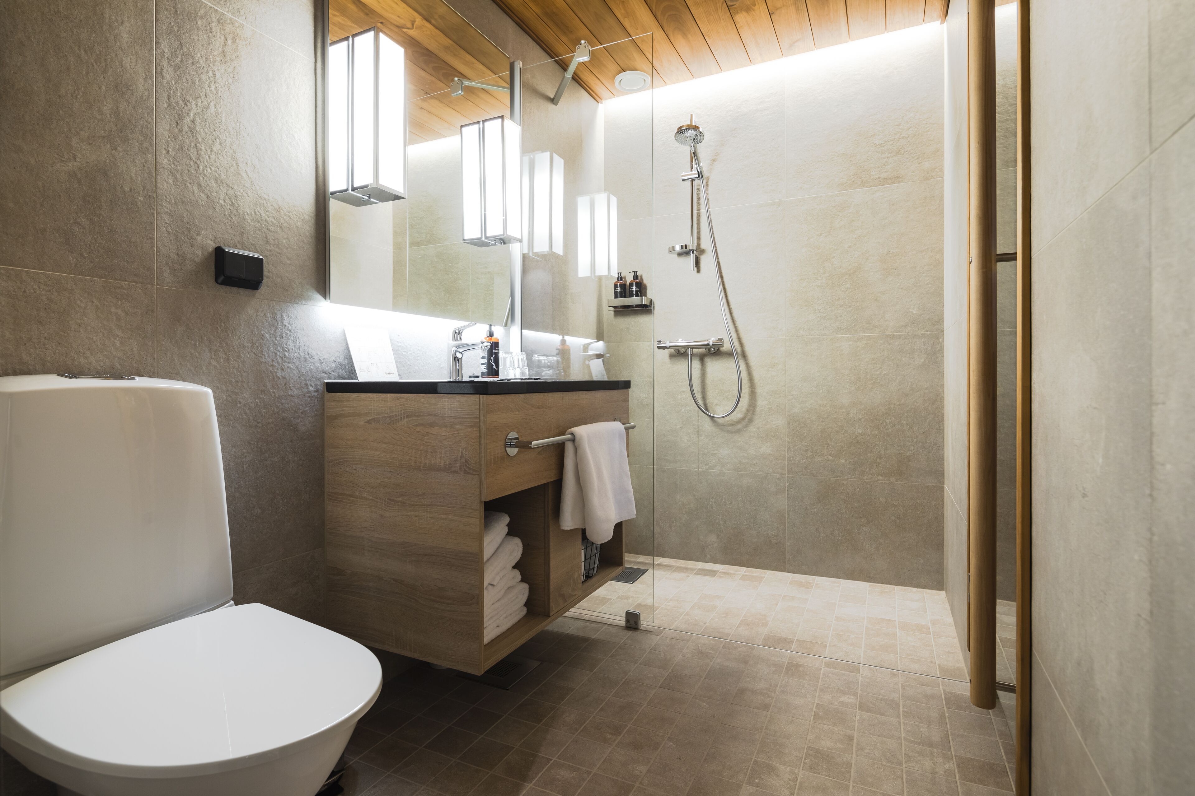A modern bathroom with a toilet, vanity, and shower.