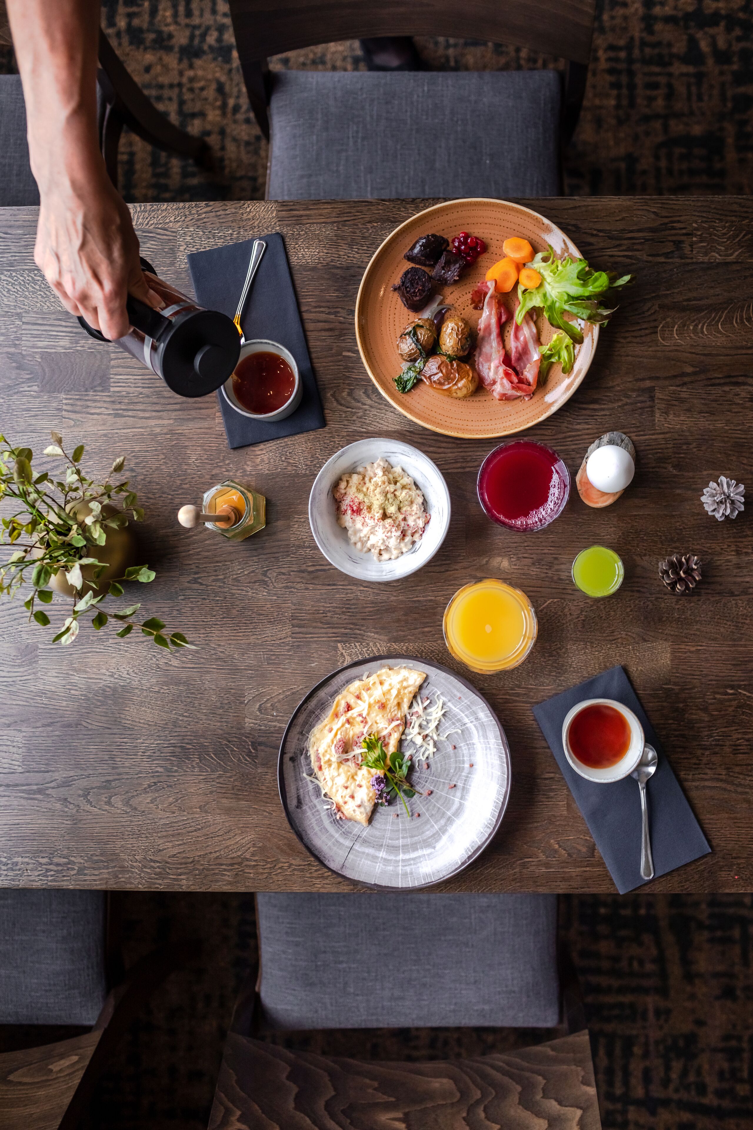 A breakfast setting with a variety of dishes including eggs, toast, and fruit, arranged on a wooden table.
