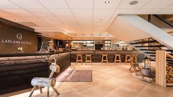 A reception area with a wooden counter, a deer's head sculpture, and a staircase.