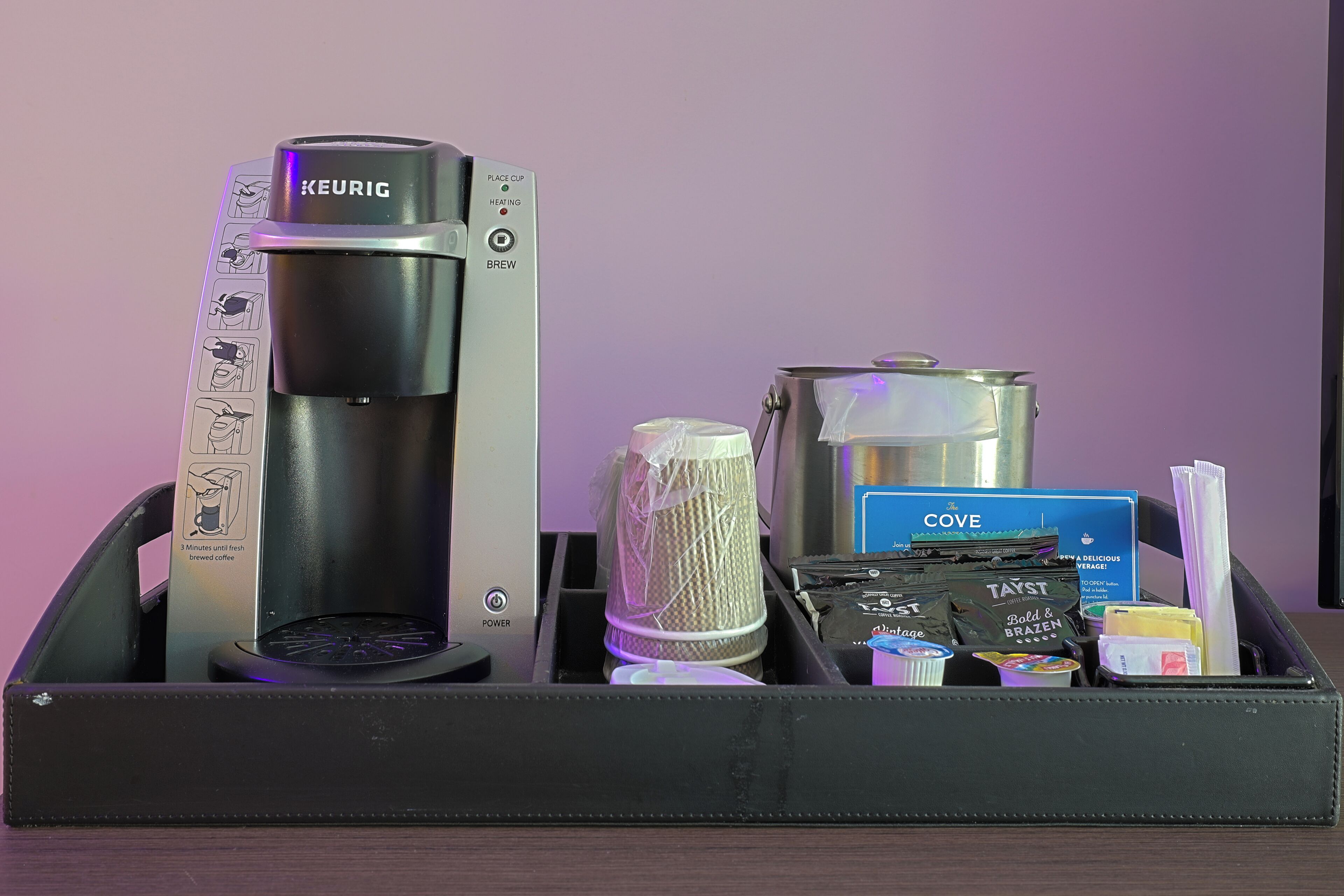 A coffee maker, a kettle, a coffee pod holder, a COVE branded coffee bag, and a travel-sized coffee mug in a travel case.