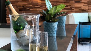 A glass pitcher with a bottle of champagne, several glasses, and a potted plant on a reflective surface. - The Cove Hotel, Long Beach (Long Beach)