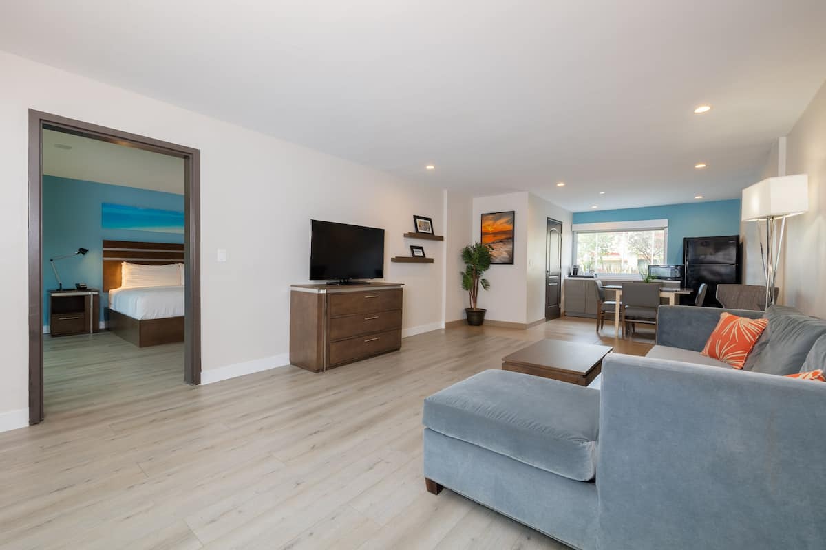 A modern living room with a grey sofa, a flat-screen TV, and a dining area with a table and chairs.